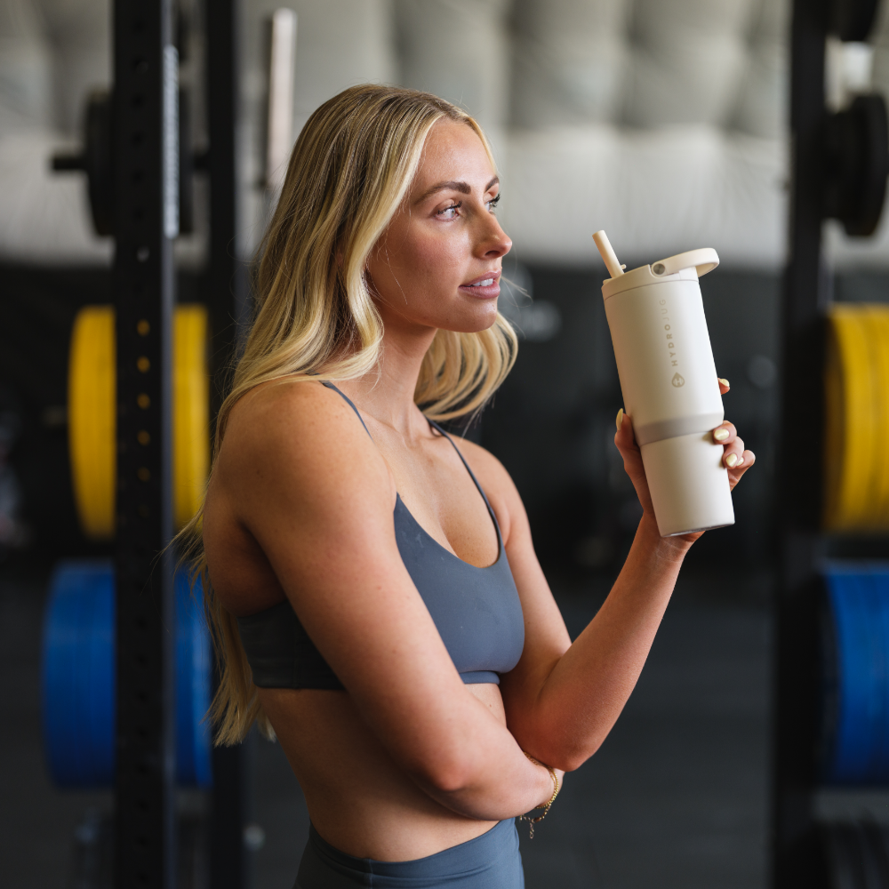 Woman Holding Tradeons Cream Sport Bottle 20oz at Gym