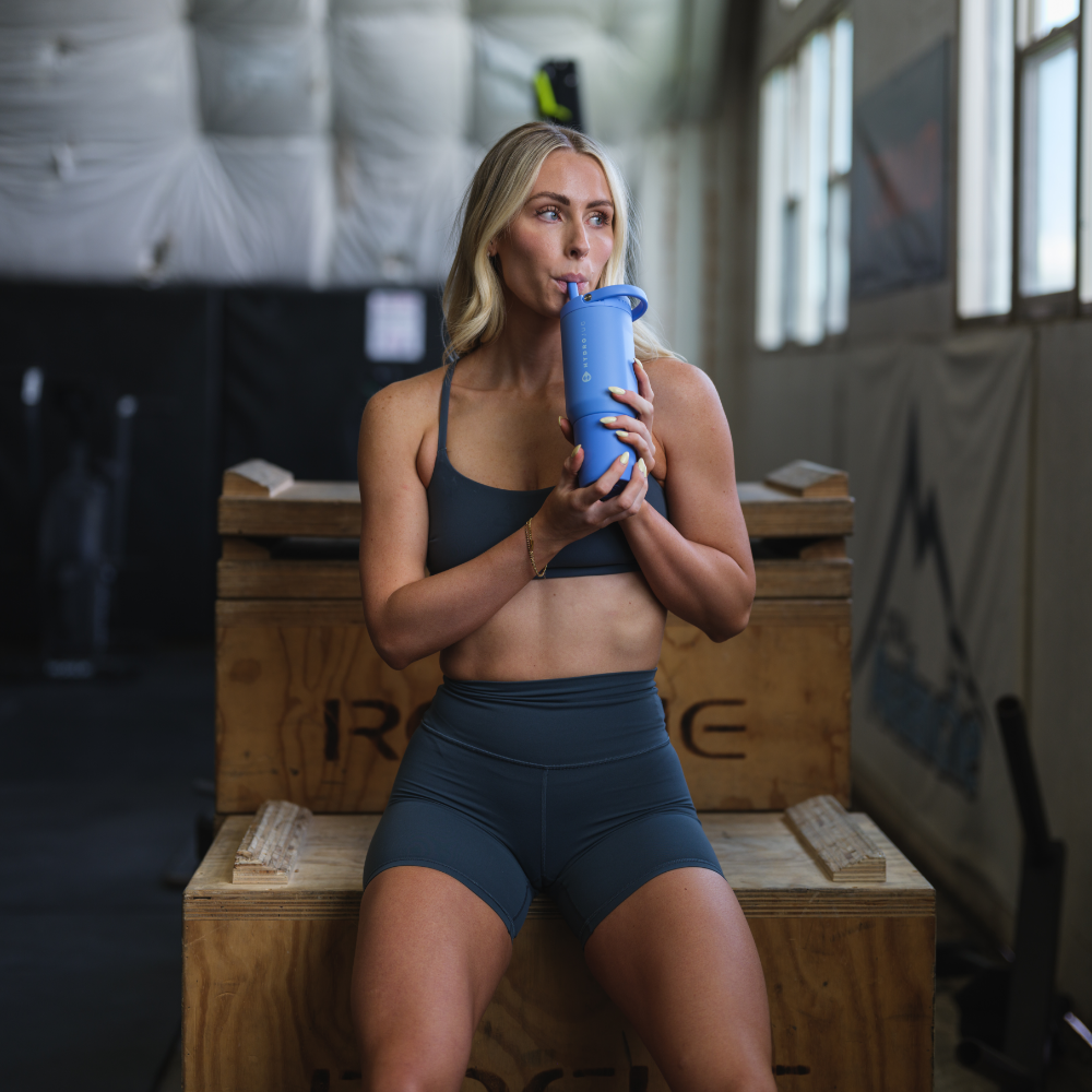 Woman Holding Tradeons Light Blue Sport Bottle 20oz in Gym